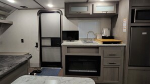 Una cocina compacta para vehículos recreativos, con horno integrado, microondas y refrigerador.
