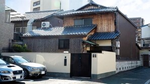 Ett traditionellt japanskt hus med en träfasad, ett tak täckt med tegelpannor och en svart port.
