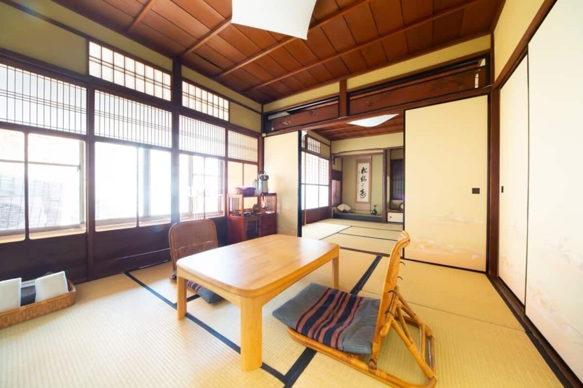 Una habitación japonesa tradicional con suelo de tatami, una mesa de madera, una zona de estar baja y puertas correderas.