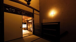 Um quarto japonês tradicional com tatames, uma porta deslizante e um candeeiro fixado na parede.