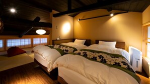 A hotel room with a large bed, wooden beams, a traditional Japanese shoji screen, and a desk with a red bag.