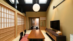 A traditional Japanese-style room with tatami flooring, a low table, a TV, and sliding doors.