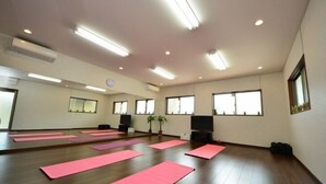 A spacious room with wooden flooring, multiple pink exercise mats, a television, and a potted plant. - Embellir (Ibaraki)