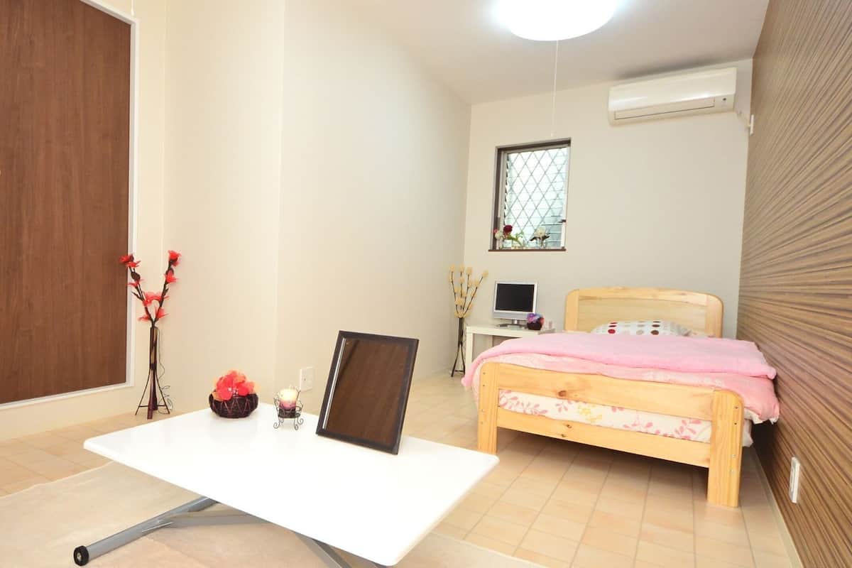 Ein Schlafzimmer mit Bett, Schreibtisch, Stuhl, Fernseher und Fenster.