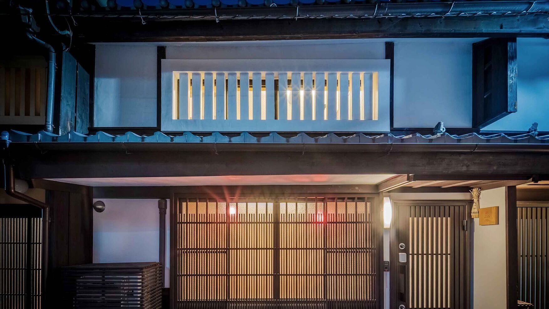 Ein traditionelles japanisches Gebäude mit hölzernem Tor, einem kleinen Schrein und einem Ziegeldach.