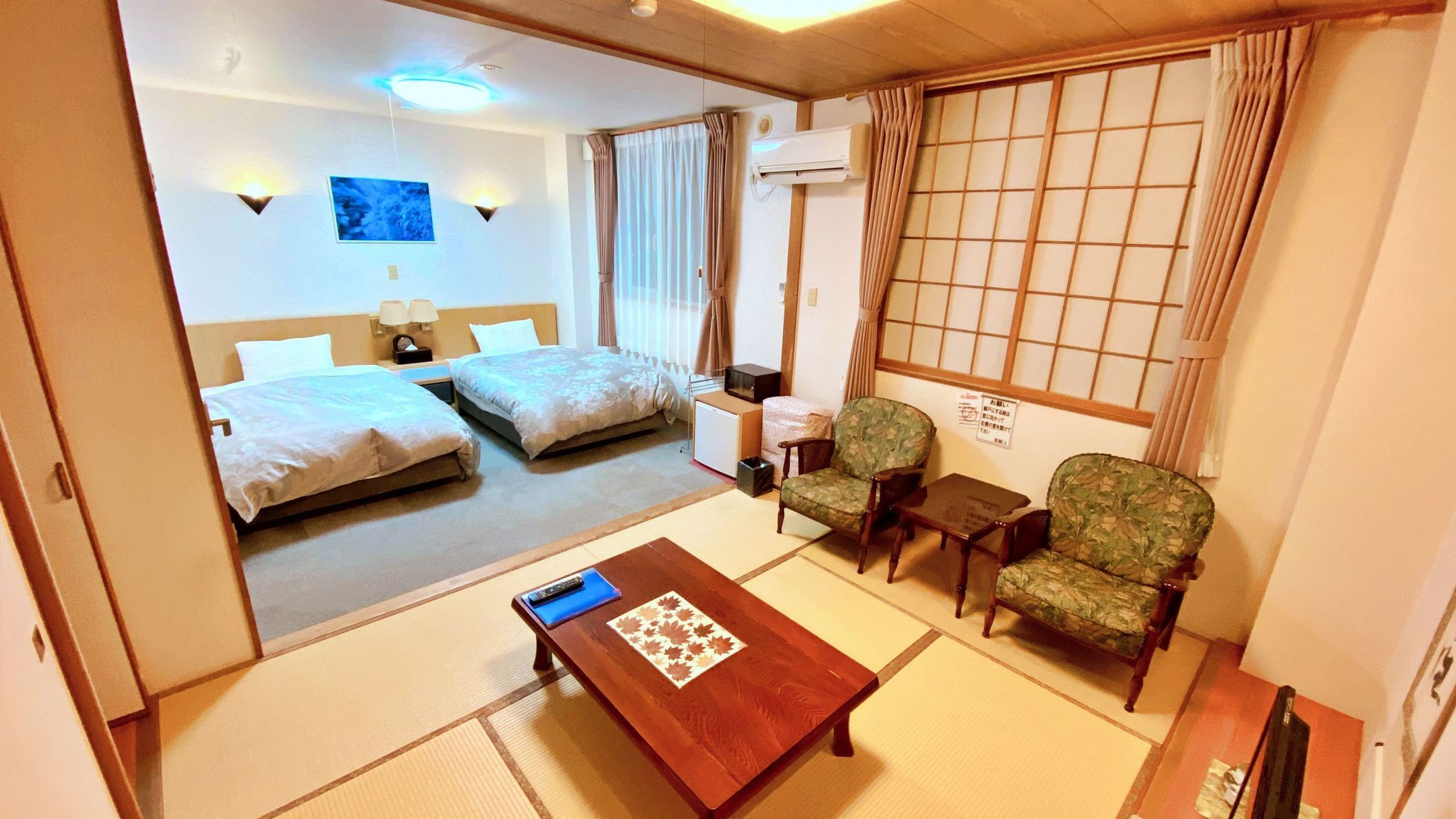 A hotel room with two beds, a sitting area with a table, chairs, and a TV.