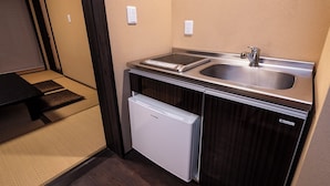 Uma cozinha compacta equipada com pia, mini-geladeira e micro-ondas.
