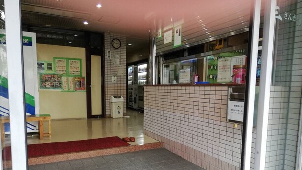 Un interno pulito rivestito di piastrelle, con una reception, una sveglia e manifesti informativi alle pareti.