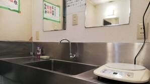 Un bagno con un lavandino in acciaio inossidabile, uno specchio e una bilancia.