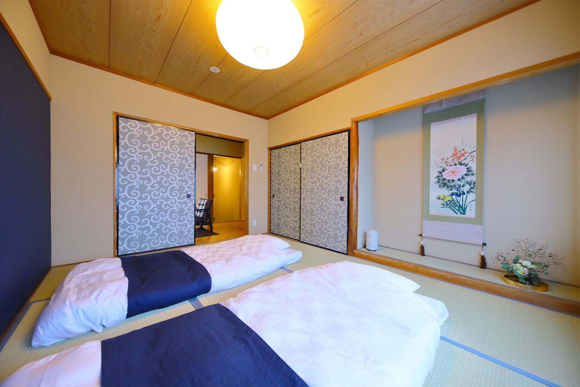 A room with two beds, a wooden ceiling, and a traditional Japanese sliding door.