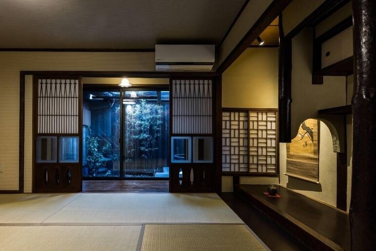 Un interior japonés tradicional con suelo de tatami, puertas correderas y un pequeño rincón con un objeto decorativo.