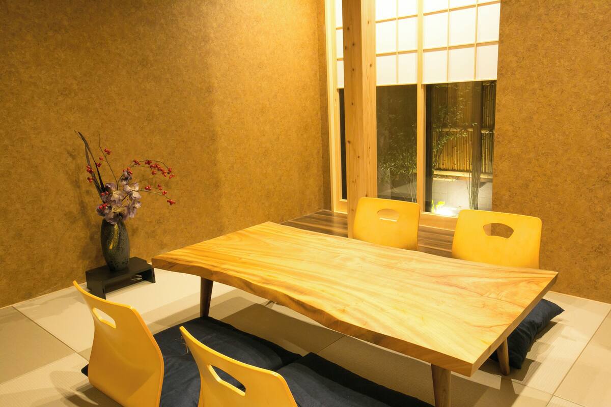 A dining area with a wooden table, yellow chairs, and a vase with flowers.
