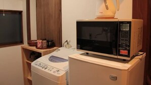 Eine kompakte Küche mit Mikrowelle, Kaffeemaschine und Waschmaschine.