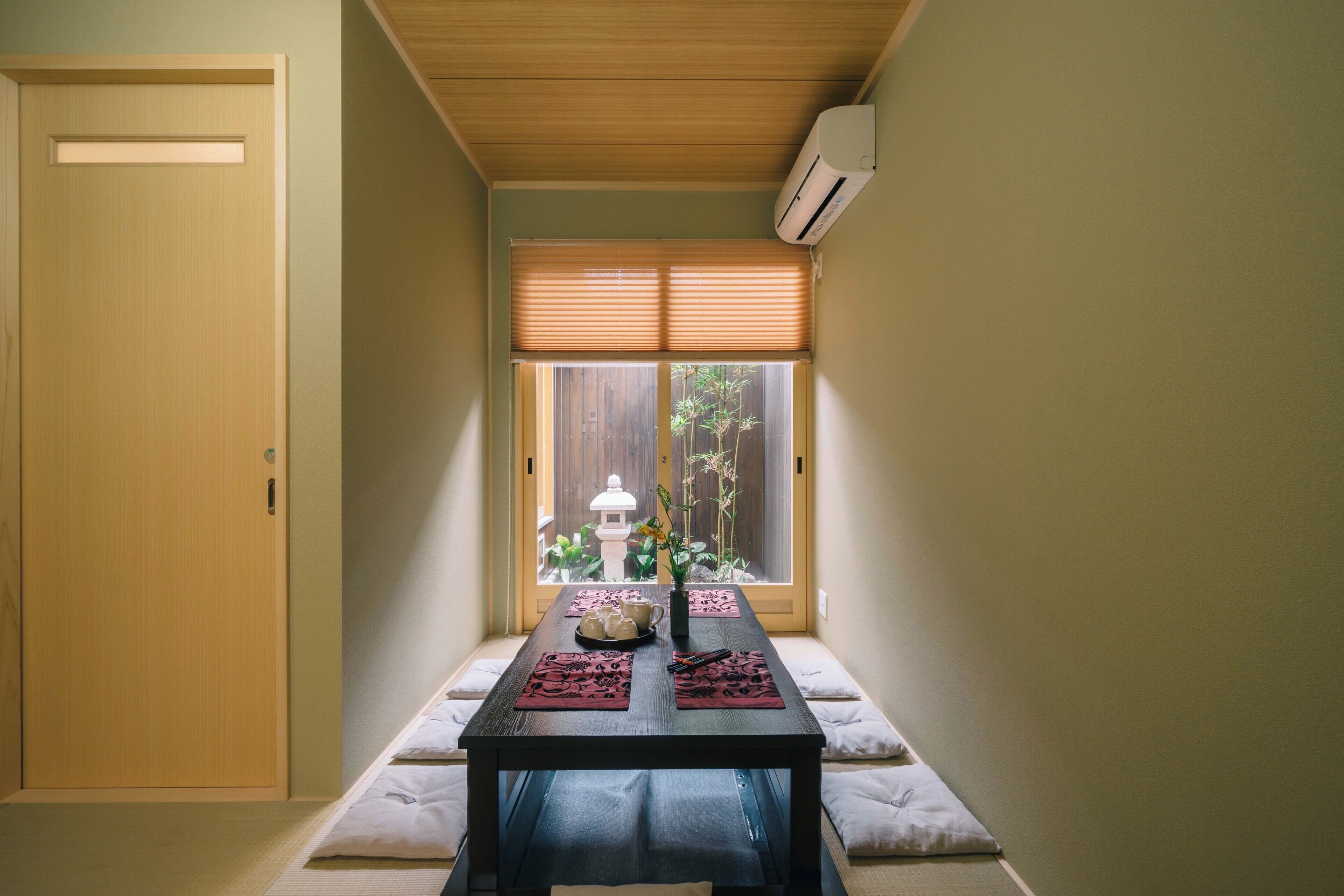 A room with a sliding door, a window with blinds, a table with placemats, and a small plant.