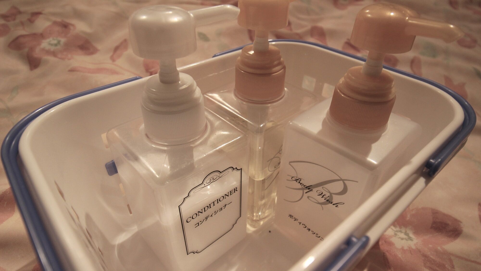 Un recipiente de plástico transparente con tres botellas, una etiquetada como 'CONDITIONER' y otra con una firma.