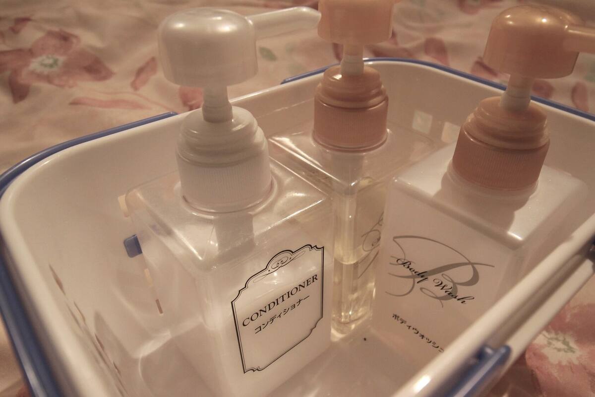 Un recipiente de plástico transparente con tres botellas, una etiquetada como 'CONDITIONER' y otra con una firma.