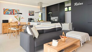 Een moderne woonkamer met een bank, eethoek, keuken en kunstwerken.