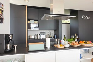 A modern kitchen with a coffee machine, a bread box, and a fruit bowl on the counter.
