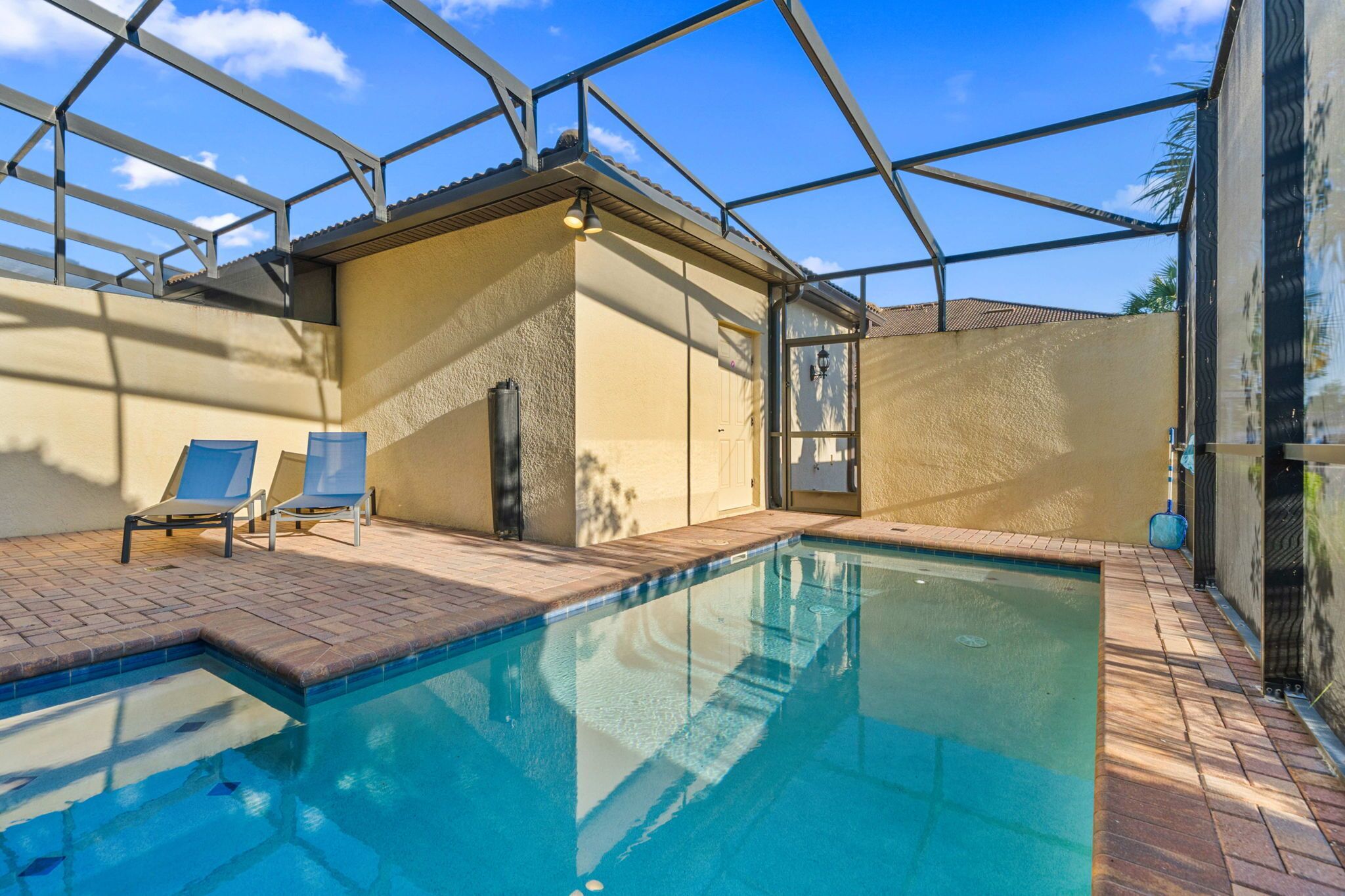 Une piscine avec deux chaises longues, un espace abrité et un ciel dégagé.