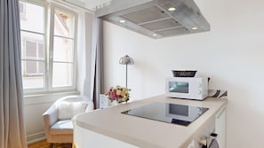 A modern kitchenette with a microwave, a small table, and a chair. - Les gîtes d'Elouise 2 (Colmar)