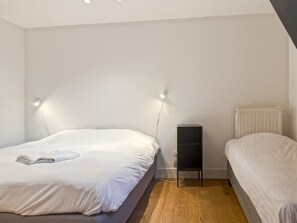 Ein Schlafzimmer mit zwei Betten, einem Nachttisch, einem Heizkörper und einer Wandleuchte.
