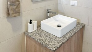 A bathroom with a white sink, a towel rack, a mirror, and a granite countertop. - Beach Walk and Direct Pool Access (Cabarete)