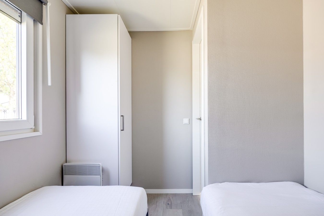 Un dormitorio con dos camas, un armario y un radiador.