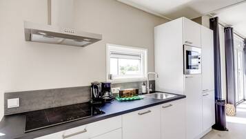 A modern kitchen with a built-in stove, a coffee maker, and a window above the sink.