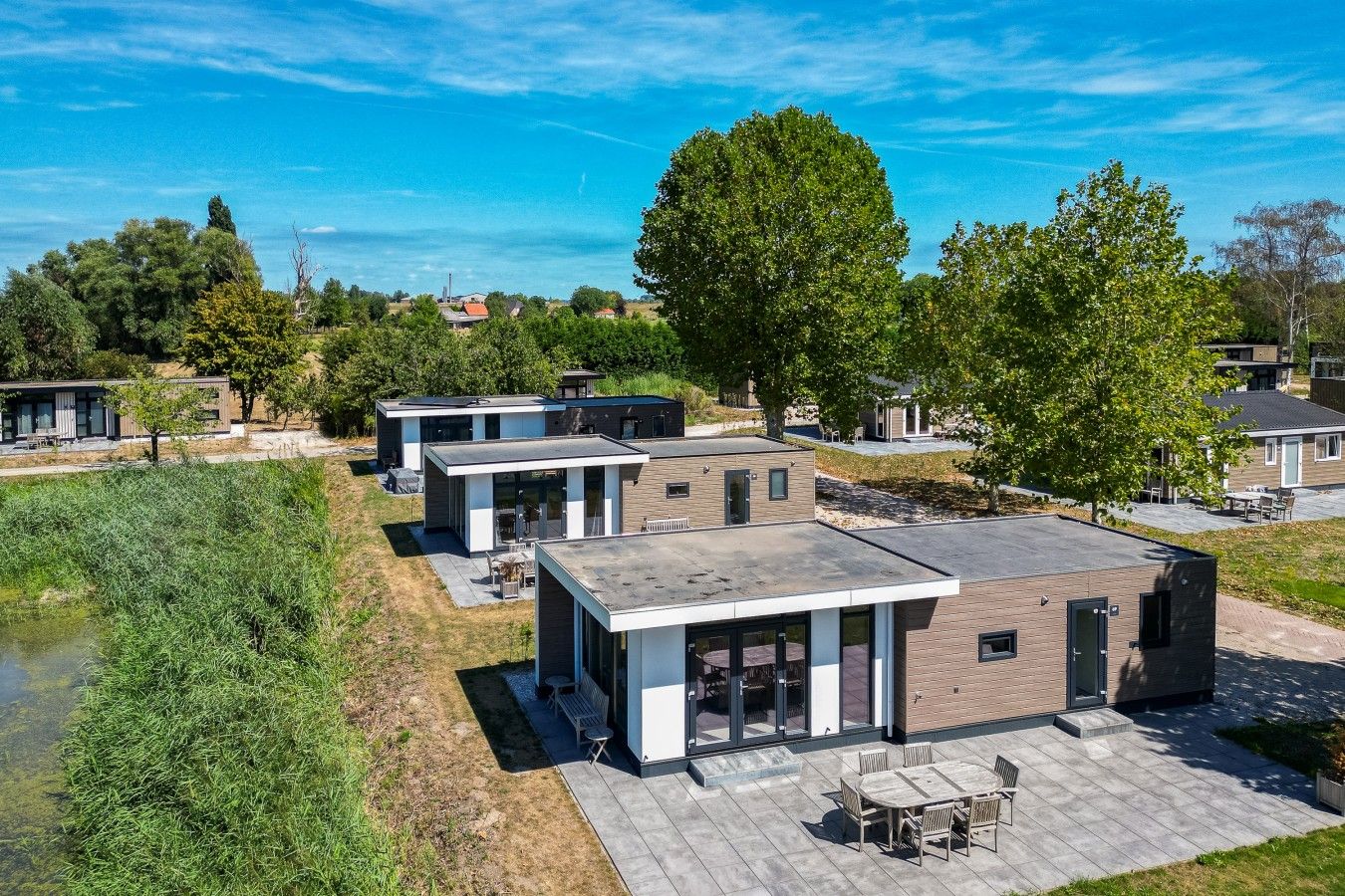 Un complejo residencial moderno con varias casas, un patio central y una masa de agua.