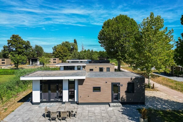 Un edificio residencial moderno con techo plano, ventanas amplias y un patio amoblado.