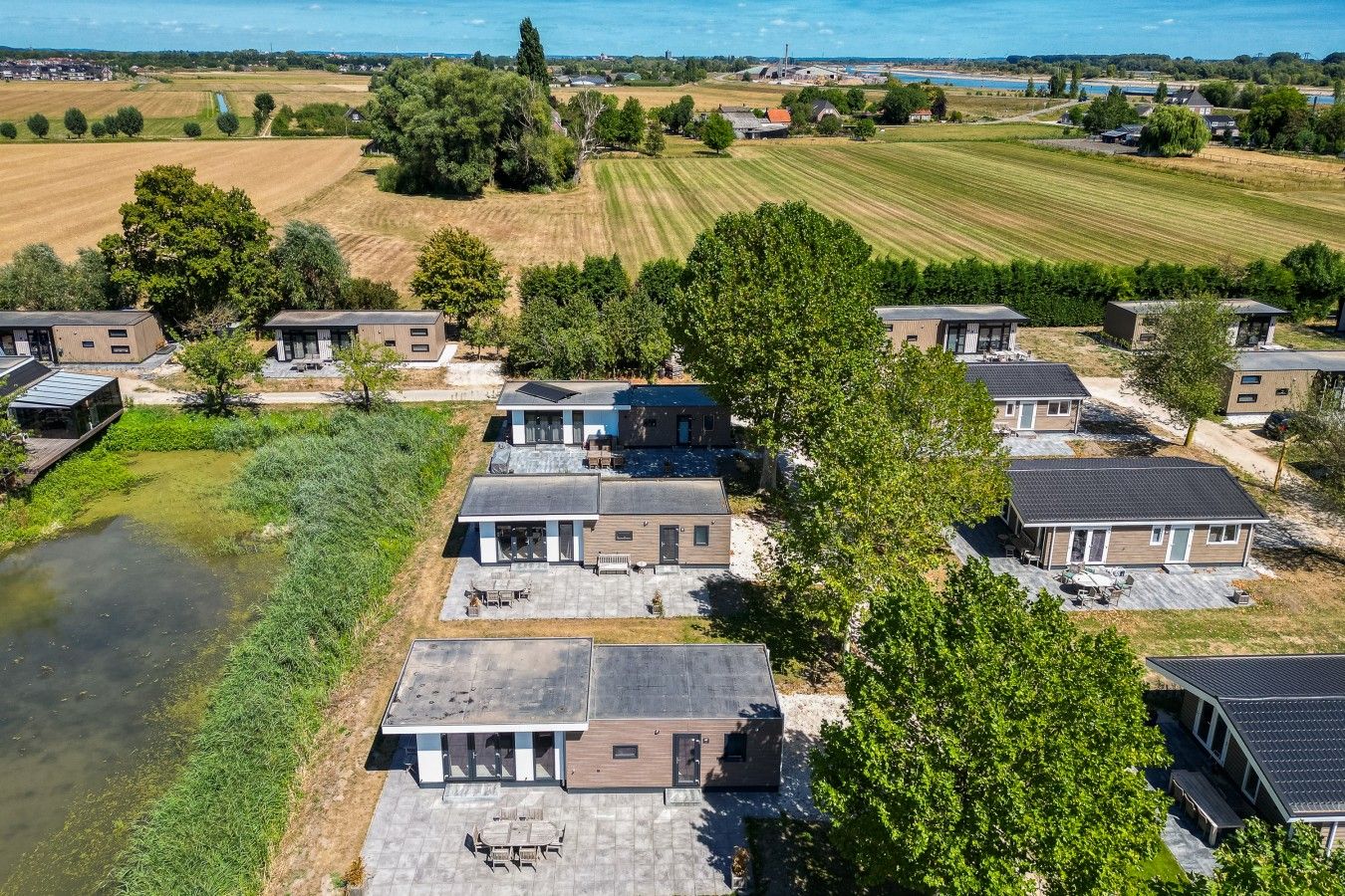 Un barrio residencial con casas modernas, un pequeño estanque y vistas al campo.