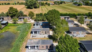Un barrio residencial con casas modernas, un pequeño estanque y vistas al campo.