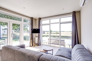 A modern living room with a grey sofa, a small round table, and a flat-screen TV mounted on the wall.