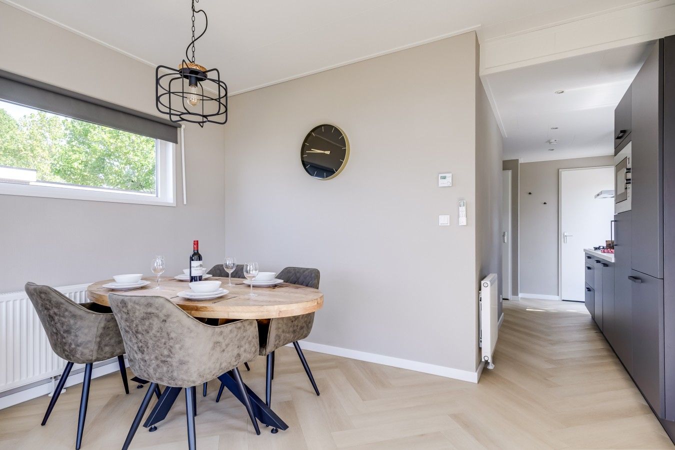 Un espace de salle à manger moderne avec une table ronde, des chaises et un luminaire suspendu.