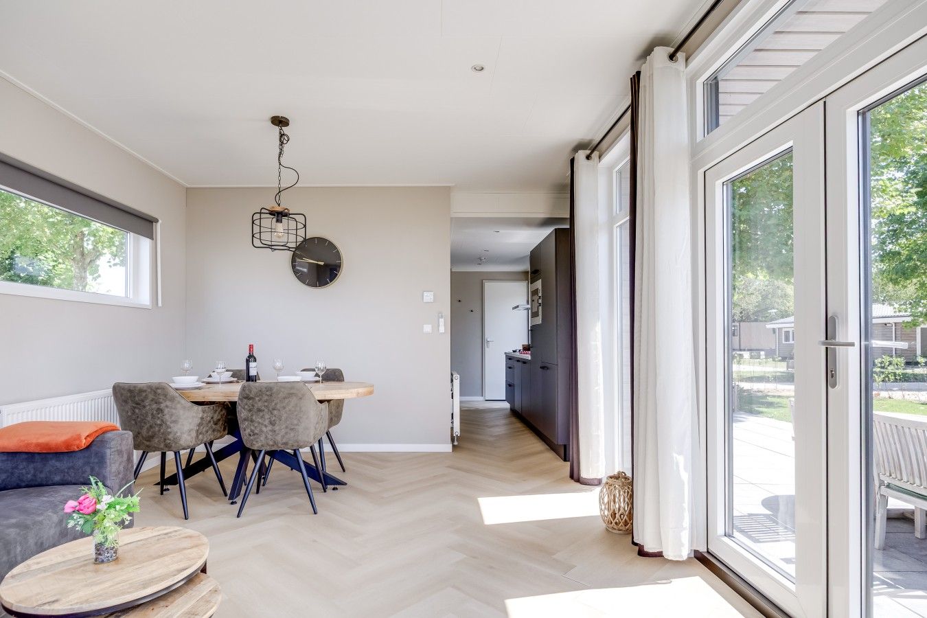 Een modern interieur met een eethoek, keuken en grote schuifpuien naar een buitenterras.