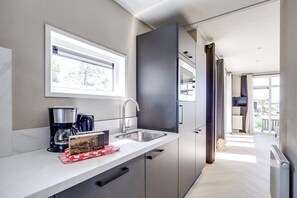 A modern kitchen with a built-in oven, a coffee maker, and a sink.