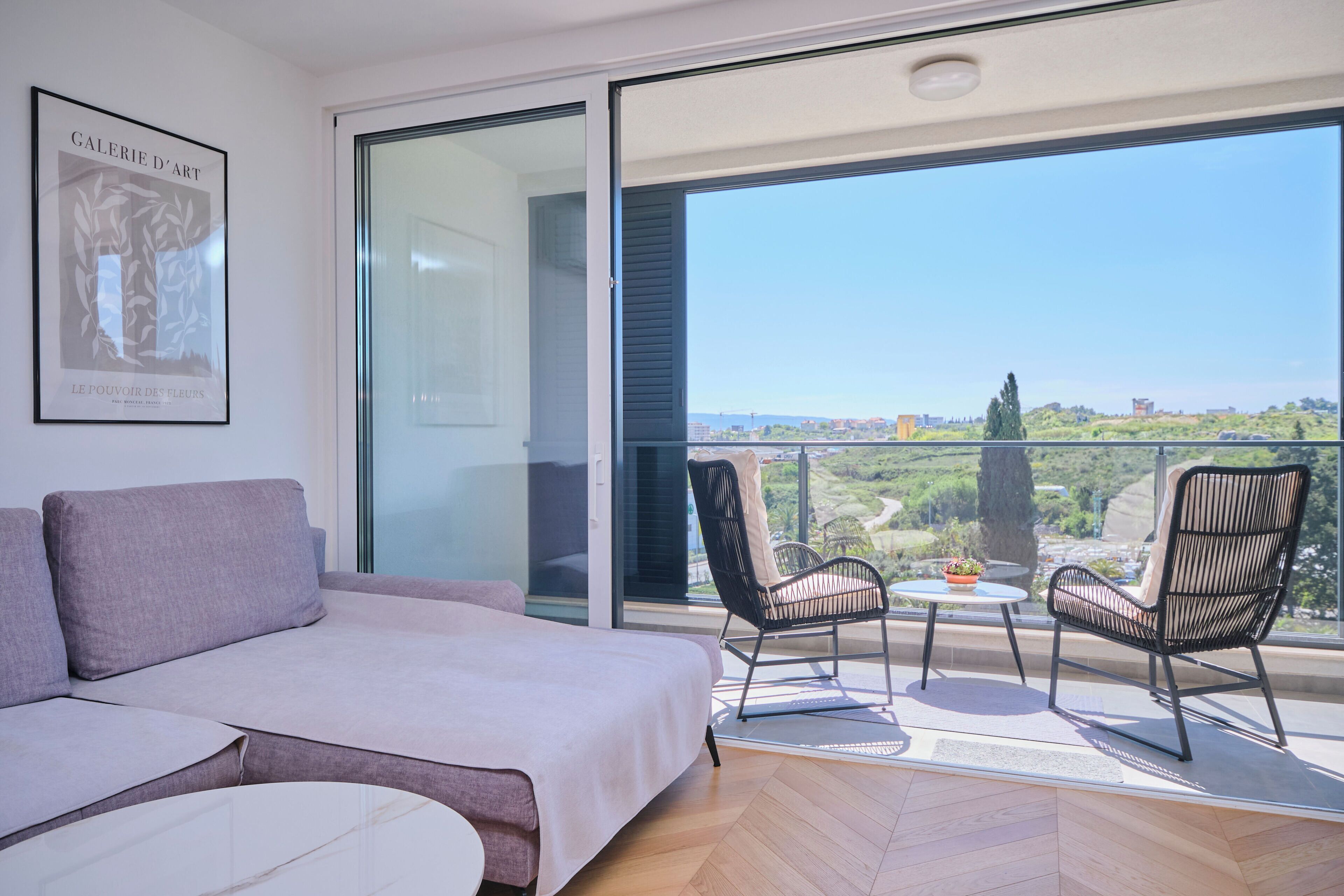 A balcony with a bed, two chairs, and a table.