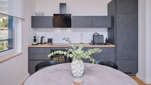 A modern kitchen with a dining table, a vase with greenery, and a coffee maker. - City Lux Suite (Split)