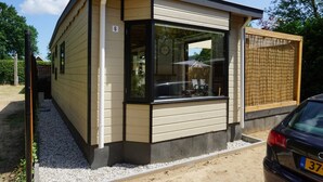 Un bâtiment moderne doté d’une grande fenêtre, d’une enseigne portant le chiffre 6 et d’une voiture garée devant.