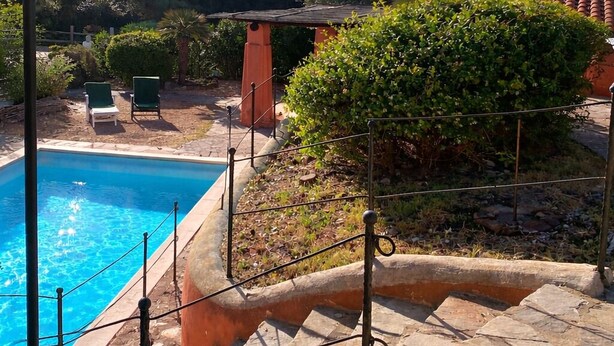 Una piscina con plataforma de piedra, un farol y vistas a colinas al fondo.