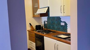 Una cocina con armarios blancos, una estufa negra y un salpicadero de azulejos.