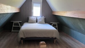 A bedroom with a sloped ceiling, a bed with white bedding, two nightstands, and a window. - Fully-equipped self-contained apartment with Jacuzzi access (Marles-en-Brie)