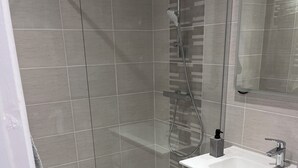 A modern bathroom with a shower, a sink, and a mirror. - Fully-equipped self-contained apartment with Jacuzzi access (Marles-en-Brie)
