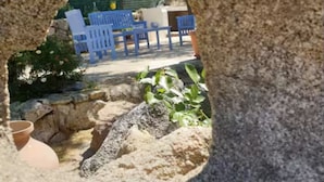 A stone structure with a view of outdoor seating and greenery. - Dependance Cugnana, surrounded by greenery and away from the chaos (Olbia)