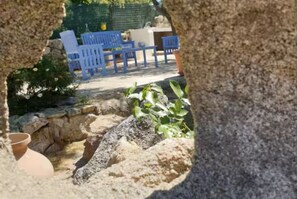 A stone structure with a view of outdoor seating and greenery. - Dependance Cugnana, surrounded by greenery and away from the chaos (Olbia)