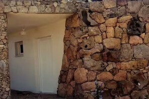 A stone wall with a doorway leading to a room. - Dependance Cugnana, surrounded by greenery and away from the chaos (Olbia)