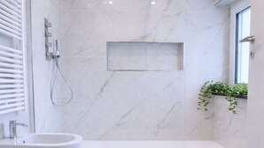 Une salle de bain moderne avec une baignoire sur pieds, un grand lavabo et un espace douche.