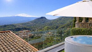 Une terrasse sur le toit avec un jacuzzi, une vue dégagée sur une montagne et un parasol blanc.