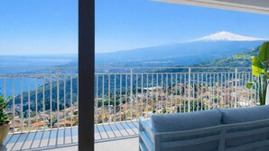Un balcon avec vue sur une ville côtière et une montagne.