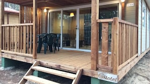 A wooden deck with a glass door entrance, outdoor seating, and a sign reading 'Gîtelet.'
